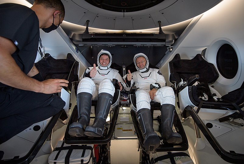 Robert Behnken, left, and Douglas Hurley are seen inside SpaceX Crew Dragon Endeavour being greeted by a crew member on board GO Navigator.