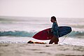 "Surfer_walking_with_board_(Unsplash).jpg" by User:Fæ