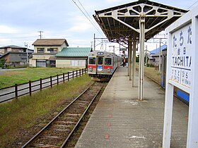 Színes fotó egy állomás peronjáról egy érkező vonattal