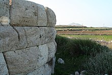 foto a colori: un muro in mezzo ai campi.