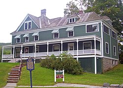 Une maison verte et blanche avec des toits pointus et des auvents