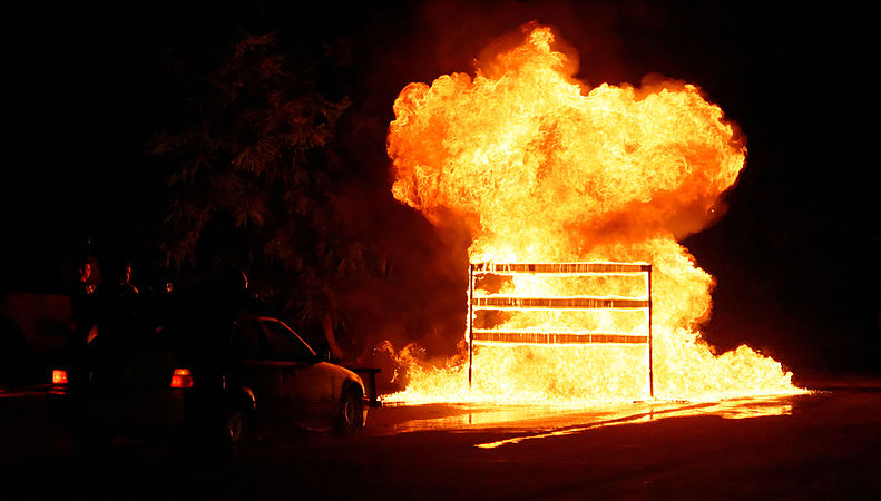 Passage dans le feu, d'une voiture à laquelle s'accroche un cascadeur (sur le toit).