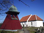 Ännu en panelklädd täckt klockstapel vid Bergums kyrka utanför Göteborg. Den lutande formen avslöjar att grundstrukturen också här är en bock