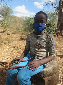 A boy wears a mask outdoors in Zimbabwe, May 2020 Boy with catapult.jpg