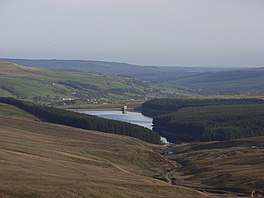 A view down a valley with a lake surrounded by trees