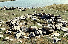 Foto dari pengaturan melingkar dari batu-batu di tanah terbuka dengan badan air di latar belakang