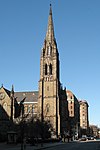 Vista a livello del suolo di una cattedrale in stile gotico con un prominente campanile ornato ad un'estremità