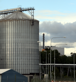 Example of Industrial Symbiosis. Waste steam from a waste incinerator (right) is piped to an ethanol plant (left) where it is used as in input to their production process. IndustrialSymbiosisWasteHeatExchange.png