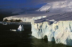 Image of barren, glacial coastline surrounded by ice cliffs and bergs