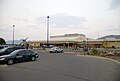 Een lokale parkeerplaats met een aantal auto's die gebruik maken van de service;  er is ook een gebouw van een luchthaven, dat een terminal bevat.