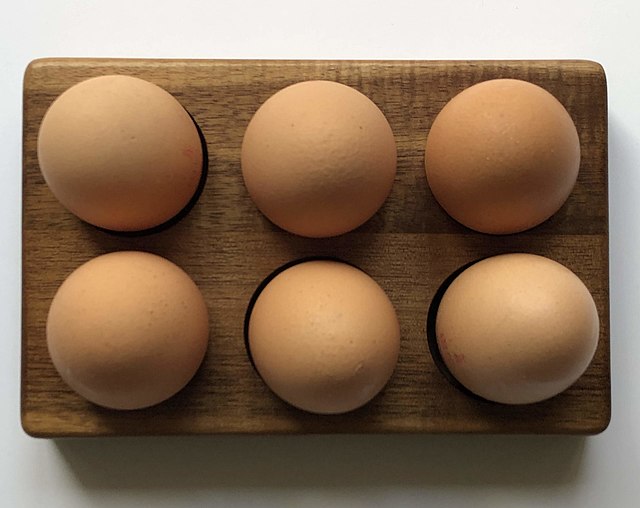 Six commercial eggs — view from the top against a white background