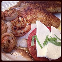Shrimp and grits con ensalada caprese y pescado ennegrecido.