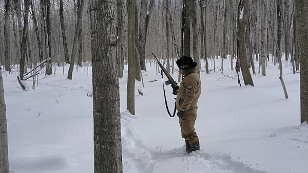An agent armed with an M14 rifle tracking someone in harsh winter conditions on the northern border.