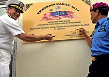 United States Navy Captain and Royal Malaysian Navy Rear Admiral together signing a dedication plaque for a new medical clinic built in Pekan, Pahang through collaboration during Cooperation Afloat Readiness and Training (Exercise CARAT) in 2011. US Navy 110611-N-NJ145-125 Capt. John W. Gilman and Royal Malaysian Navy Rear Adm. Nasaruddin bin Othman ign the dedication plaque during the turno.jpg