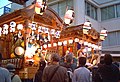 市内を練り歩く山車の上段で祭囃子を披露