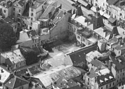 Vue aérienne de la façade arrière du bâtiment historique et de la cour avec fontaine, en avril 1935.