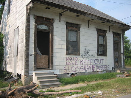 Graffiti représentatif de l'impopularité du NOPD sur une maison du Lower Ninth Ward (en), l'un des quartiers les plus dévastés par l'ouragan. Il est écrit : « NOPD sucks » (« le NOPD craint ») et « Keep out Grave robbers » (« Pilleurs de tombe, dehors ! »).
