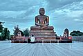 Gran estatua al aire libre de Mahavira, con un adorador sentado para escalar