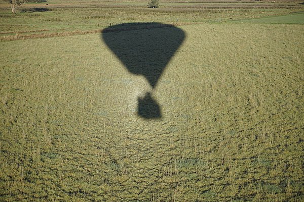 "Aura" around the shadow of a hot-air balloon, caused by retroreflection from dewdrops