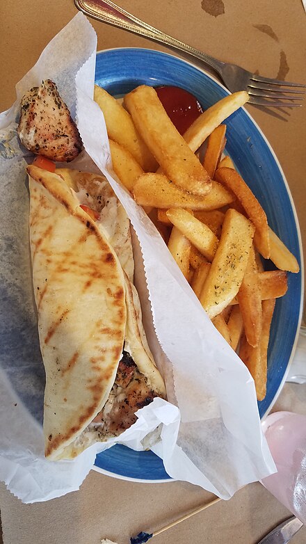 Chicken souvlaki pita served with a side of French fries in a restaurant in the United States