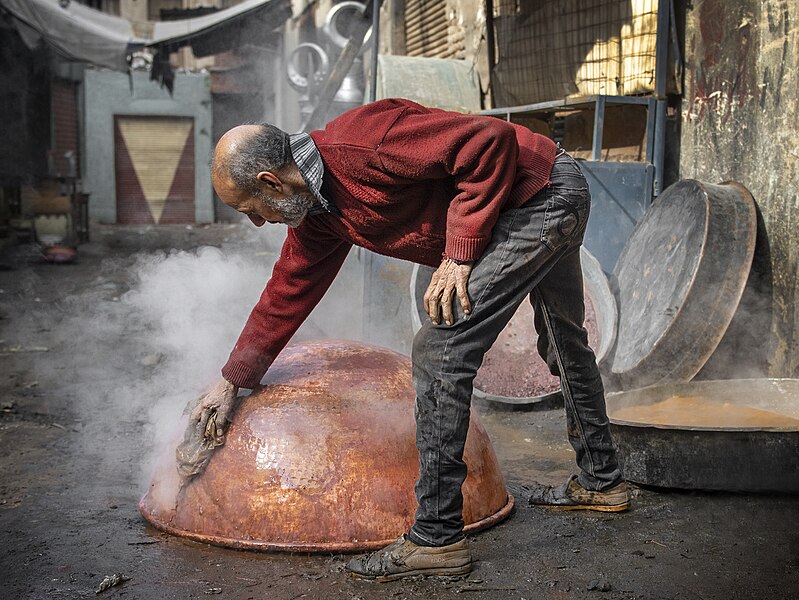 A man performing bleaching process on copper utensil by Summering2018