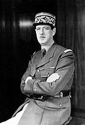 Charles de Gaulle seated in uniform looking left with folded arms