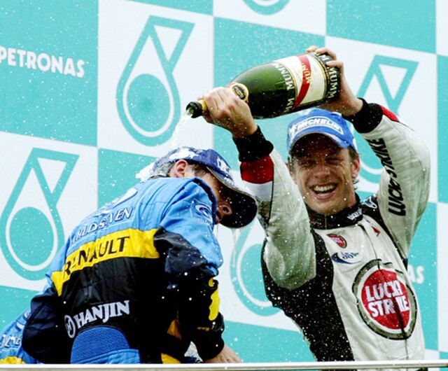 Jenson Button pouring champagne on Giancarlo Fisichella during the podium ceremony after the race.
