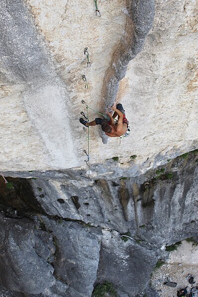 Climber leading the sport climbing route Hulkosaure 8b (5.13d). Quickdraws have already been attached to the line of pre-drilled bolts that mark the r