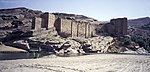 Ruins of a dam built in old Arabian architecture, with rocky mountains in the background .