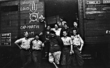 Soldats devant un wagon couvert, portant les inscriptions à la craie : l'héroïque E.O.15 et Cap-Saint-Martin