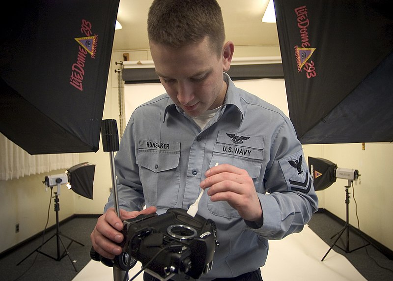 File:US Navy 050217-N-5134J-002 Photographer's Mate 2nd Class Lewis Hunsaker of Brownsville, Ore., uses a brush to clean a studio camera in the photo lab on board Naval Station Everett, Wash.jpg