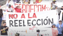 Manifestantes del 1 de mayo de 2023 sosteniendo una pancarta con un mensaje contra la reelección.