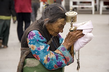 Yaşlı bir Tibetli kadın Barkhor'da Lhasa hacı yolunda elinde bir dua çarkı tutarken. (Üreten:Lucag)
