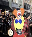 Clowns are often associated with the pie-in-the-face gag. An auguste clown holds a pie at a parade.