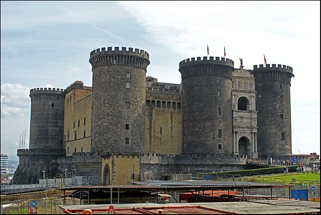 Castel Nuovo seen from the northwest in 2014. The main entrance is through a triumphal arch between two tall round towers.
