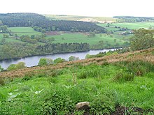 View across a partially wooded valley containing a reservoir