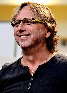 Close-up of middle-aged white man with facial stubble, wearing glasses, looking to the left of the camera