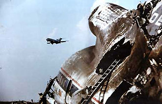 Wreckage of Delta Air Lines Flight 191 tail section after a microburst slammed the aircraft into the ground. Another aircraft can be seen flying in the background past the crash scene. Delta 191 wreckage.jpg
