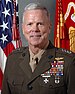 A color image of James Amos, a white male in his Marine Corps Service A uniform. He is not wearing a hat, several ribbons are visible as well as a rifle and pistol marksmanship badges and naval aviator insignia. The Marine Corps flag and United States flag are visible in the background.