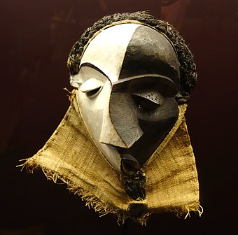 Mbangu mask; wood, pigment & fibres; height: 27 cm; by Pende people; Royal Museum for Central Africa. Representing a disturbed man, the hooded V-looking eyes and the mask's artistic elements – face surfaces, distored features, and divided colour – evoke the experience of personal inner conflict