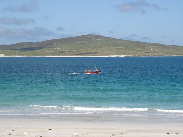 A fishing boat passes between the west beach of Berneray and the island of Pabbay