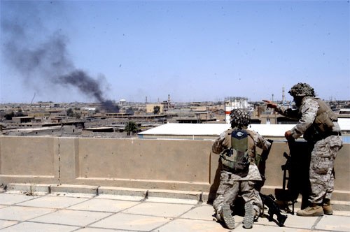 Marines with A/1/5 peer over a building top to fix enemy targets in Al Fallujah, Iraq 7 April 2004.