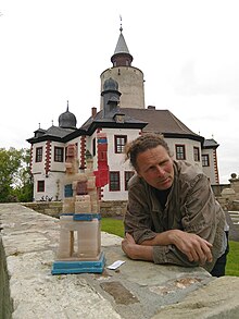 Wolfgang Stöcker mit einem seiner "Staubtürme" vor dem Thüringer Museum Burg Posterstein. Für die Ausstellung "Zum Wesen des Staubes – Staubexpeditionen auf Burg Posterstein" entstanden zahlreiche Kunstwerke.