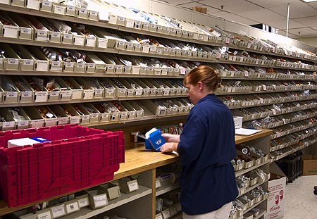 US Navy 030819-N-9593R-078 A Navy hospital corpsman unwraps medication to replenish one of the hundreds of bins in the pharmacy at the National Naval Medical Center in Bethesda, Maryland.jpg