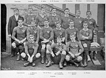 Photo de l'équipe du pays de Galles de rugby à XV prise avant la rencontre contre l'Angleterre lors du Tournoi britannique de 1895. Les quinze joueurs ainsi que l'entraîneur sont disposés sur trois rangées : trois joueurs sur celle du bas, six sur celle du milieu et les six derniers ainsi que l'entraîneur sur celle du haut.