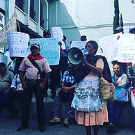 Guatemaltekische Frau spricht mit anderen Demonstranten im Hintergrund in ein Megaphon