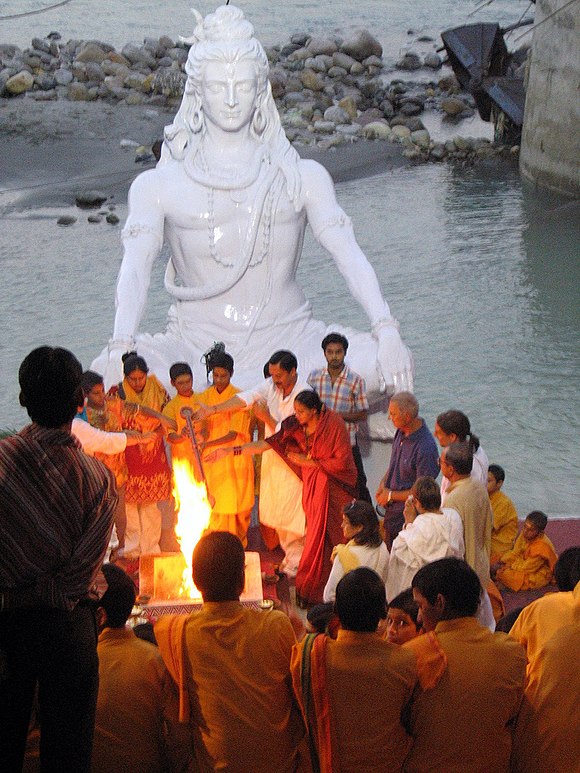 Siva nella postura del sukhasana; statua situata sulla riva del fiume Gange, nella città di Rishikesh, India del Nord. La città, soprannominata "capitale mondiale dello Yoga", è sede del Kailas Ashram Brahmavidyapeetham, un importante centro di studi sul Vedānta; meta di studiosi, pellegrini e turisti, ospitò, nel 1968, anche John Lennon.