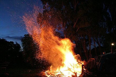 A bonfire in rural Australia, with a large number of sparks being blown by the wind; sparks are akin to embers in a similar way that dust is to stone.