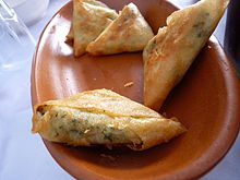 La fotografía muestra un plato coronado con cuatro ladrillos fritos con guarnición.  Las porciones son triangulares.  El rebote de su cara indica la presencia de relleno.  Por transparencia, adivinamos hierbas aromáticas.  El color dorado de los ladrillos indica cocción frita.