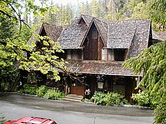 Photograph of the front of the Oregon Caves Chateau, surrounded by forest, on a wet day.